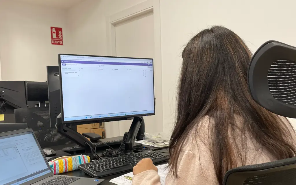 Persona trabajando en una oficina frente a un ordenador con Odoo abierto para gestionar procesos empresariales